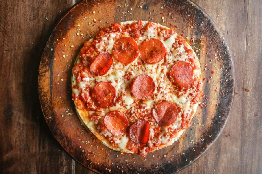 Leckere ofenfrische Pepperoni Pizza schon auf einem Brett auf dem Tisch angerichtet wie bei der Pizzeria Avanti mit Lieferservice in Hof.